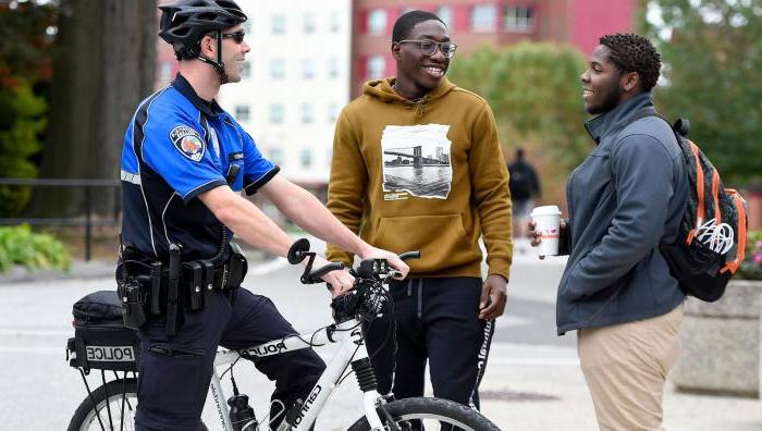 An officer on a bicycle has a discussion with two students