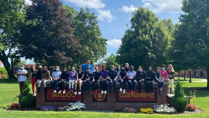 7th grade students visiting campus sitting on Springfield College sign